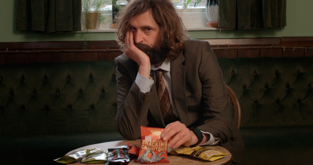 STILL OF JOE WILKINSON WITH A PACK OF SERIOUS PIG SNACKS